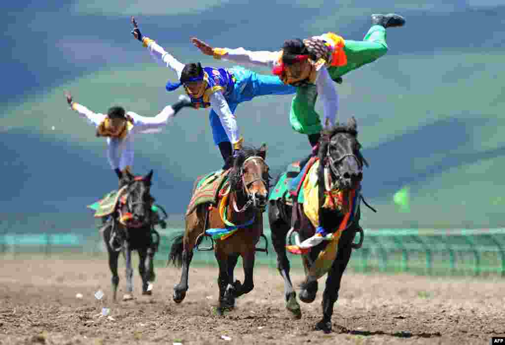 Riders wearing ethnic group costume compete in a traditional horseback riding event in Hongyuan county of Aba town, or Ngawa town, southwest China&#39;s Sichuan province, June 17, 2014.