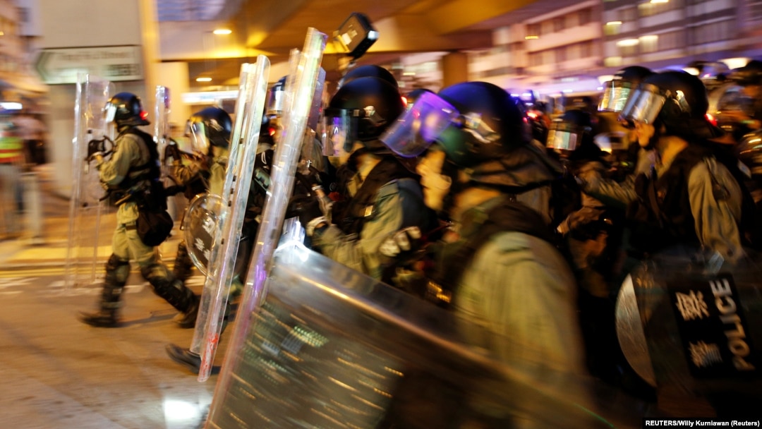 Polisi anti huru hara Hong Kong mengejar para demonstran setelah terjadi bentrokan dalam aksi protes di Kowloon Bay, Sabtu (24/8). 