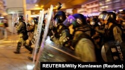 Polisi anti huru hara Hong Kong mengejar para demonstran setelah terjadi bentrokan dalam aksi protes di Kowloon Bay, Sabtu (24/8). 