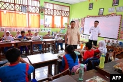 FILE - Presiden Indonesia Prabowo Subianto (kedua dari kanan) meninjau pelaksanaan program makanan bergizi gratis (MBG) di sebuah ruang kelas Sekolah Dasar Negeri Jati 05 Pagi, Jakarta Timur, 3 Februari 2025.. (Handout / Istana Kepresidenan Indonesia / AFP)