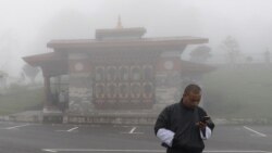 a Bhutanese man looks at his phone on a foggy day at Dochula Pass.