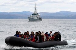 Migrants arrive with a dinghy accompanied by a Frontex vessel at the village of Skala Sikaminias, on the Greek island of Lesbos, after crossing the Aegean sea from Turkey, Feb. 28, 2020.