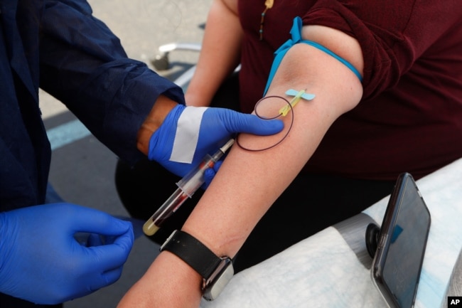 FILE - In this Friday, June 12, 2020 file photo, a woman has blood drawn for COVID-19 antibody testing in Dearborn, Mich.