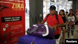 FILE - Travelers walk past a poster with information about the Zika virus during a campaign by Peru's Health Ministry at Plaza Norte bus station in Lima, Peru, Feb. 4, 2016. 