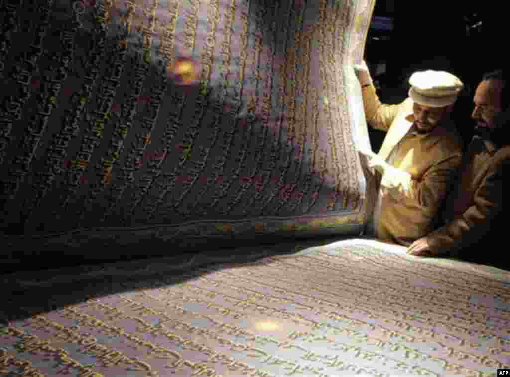 Mohammad Saber Yaqoti Hussaini Khedri, second right, the calligrapher of the world's biggest copy of the holy Quran turns a page at a ceremony in Kabul, Afghanistan, Thursday, Jan. 12, 2012. Hussaini Khedri claims to have completed the writing of the worl