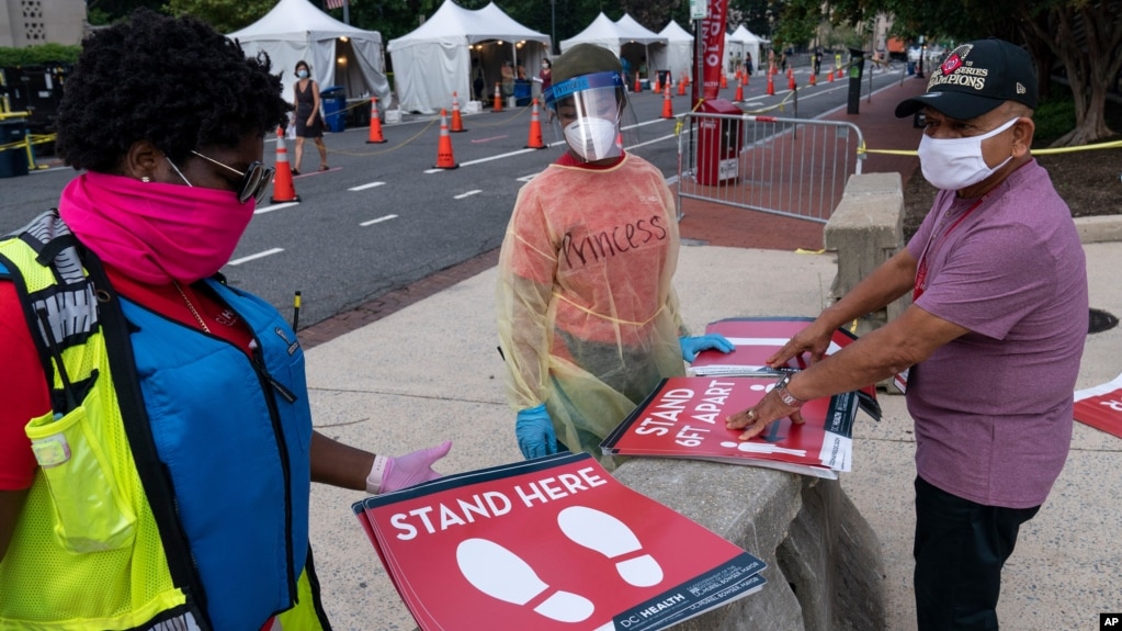 Members with the Washington, D.C. Dept. of Health, prepare to place new signs at their F Street COVID-19 testing location, Aug. 14, 2020, in Washington. This location tests approximately 450-500 people a week and has been open since June 1st. (AP…
