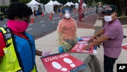 Members with the Washington, D.C. Dept. of Health, prepare to place new signs at their F Street COVID-19 testing location, Aug. 14, 2020, in Washington. This location tests approximately 450-500 people a week and has been open since June 1st. (AP…