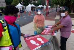 Members with the Washington, D.C. Dept. of Health, prepare to place new signs at their F Street COVID-19 testing location, Aug. 14, 2020, in Washington.