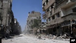In this photo taken during a Syrian government-led media tour, buildings damaged during battles between Syrian troops and rebels stand along an empty street in Mleiha, about 10 kilometers (6 miles) southeast of downtown Damascus, Syria, Aug. 15, 2014. 