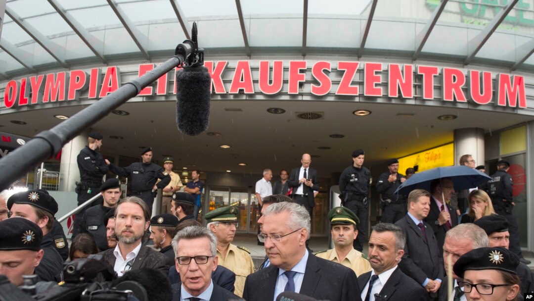 German Interior Minister Thomas de Maiziere, left, and Bavaria's Interior Minister Joachim Herrmann, right, give a media conference in front of the Olympia shopping center where a shooting took place leaving nine people dead the day before in Munich, Germany, Saturday, July 23, 2016. 