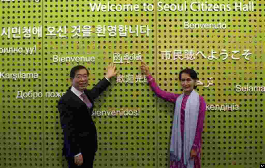 Myanmar's opposition leader Aung San Suu Kyi, right, poses with Seoul Mayor Park Won-soon as they point Myanmar characters reading "Welcome" at Seoul Citizens Hall in Seoul, South Korea, Tuesday, Jan. 29, 2013. (AP Photo/Lee Jin-man, Pool)
