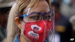 A supporter of presidential candidate Pedro Castillo wears a mask with Castillo's face during a march in Lima, Peru, June 9, 2021. 