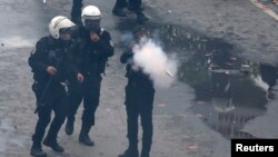 A riot police officer fires tear gas to push back protesters during a May Day demonstration in Istanbul, May 1, 2014. 