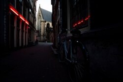 FILE - A lone man walks past closed brothels in the capital's famous red-light district on a weekend night in the center of Amsterdam, Netherlands, March 20, 2020.