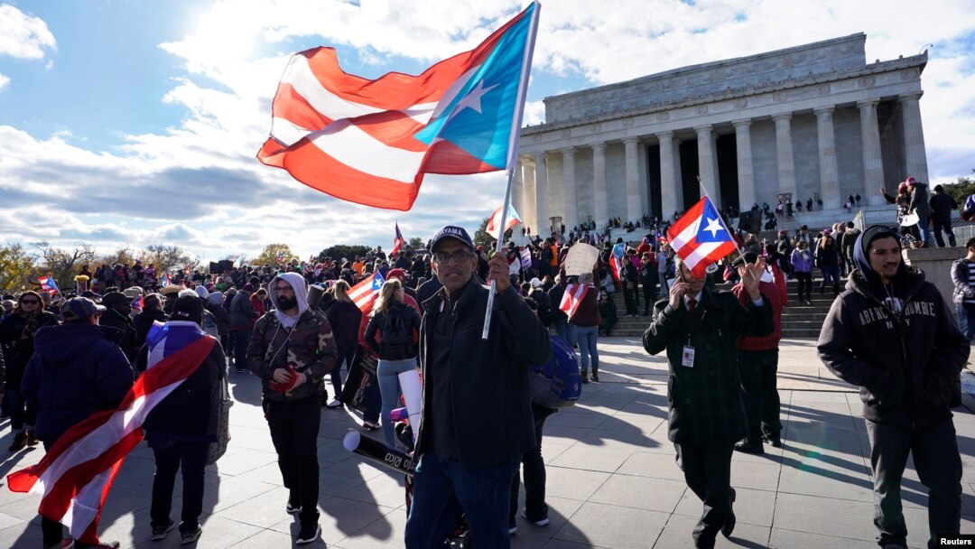 Ribuan demonstran membawa bendera nasional Puerto Rico dalam aksi demonstrasi di Washington DC hari Minggu (19/11). 