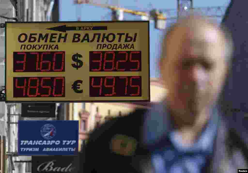 The Russian rouble hit new historic lows against the dollar on Monday, falling to 38 roubles per dollar. Here, a man walks past a board displaying currency exchange rates in Moscow, Sept. 15, 2014.