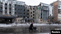 A woman walks past a building damaged by a Russian military strike, amid Russia's attack on Ukraine, in the town of Pokrovsk in Donetsk region, Ukraine, Dec. 12, 2024. 