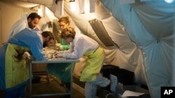 FILE - Forensic scientist Cristina Cattaneo, right, and her team collect post-mortem data from shipwreck victims to obtain information for a future identification at the NATO base in the Sicilian town of Melilli, Italy, Oct. 8, 2016.