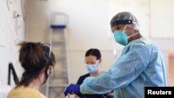 A healthcare worker prepares to conduct a coronavirus disease (COVID-19) test on a patient at a testing facility in Melbourne, Australia, Aug. 20, 2020. 