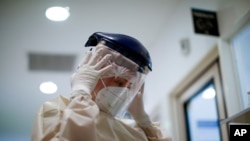 Health care worker Raquel Benitez puts on a face shield as she prepares to attend to a COVID-19 patient at the Eurnekian Ezeiza Hospital on the outskirts of Buenos Aires, Argentina, July 14, 2020.