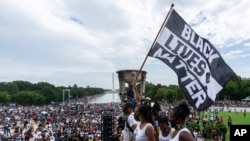 지난해 마틴 루터 킹 목사의 워싱턴 행진 연설 57주년을 맞아 링컨기념관에서 열린 집회 참가자가 '흑인의 목숨도 소중하다(Black Lives Matter)' 운동 깃발을 들고 있다. (자료사진)