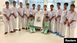 12 anak Thailand anggota tim sepakbola "Wild Boars" bersama pelatih mereka, berpose bersama gambar Samarn Kunan, mantan penyelam AL Thailand yang tewas - dalam upaya penyelamatan mereka dari gua Tham Luang - di rumah sakit Chiang Rai Prachanukroh, Chiang Rai, Thailand. 