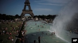 FILE - People cool off in the fountains of the Trocadero gardens, in front of the Eiffel Tower, in Paris, June 28, 2019. 