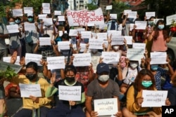 Para pengunjuk rasa memegang slogan yang mengutuk pemerintah militer dalam festival Thingyan, Selasa, 13 April 2021 di Yangon, Myanmar.