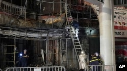 Fire personnel inspect a building burned down by a fire in Hanoi, Vietnam, Dec.19, 2024.