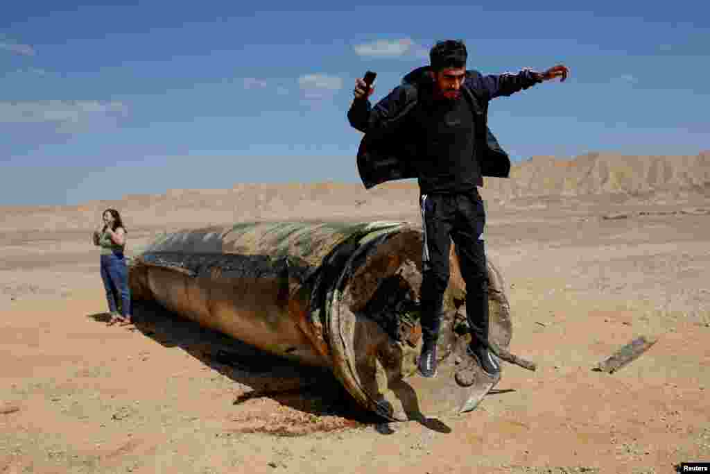 A man jumps off apparent remains of a ballistic missile lying in the desert, following an attack by Iran on Israel, near the southern city of Arad.