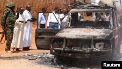 Security officers and government officials inspect a police car that was burnt during an attack on a convoy escorting the governor of Mandera region Ali Roba outside Mandera town, near Kenya's border with Somalia and Ethiopia, March 13, 2015. 