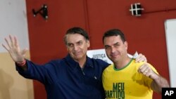 Presiden Brazil Jair Bolsonaro, saat kampanye pilpres, bersama putranya, Flavio, di tempat pemungutan suara di Rio de Janeiro, Brazil, 7 Oktober 2019.