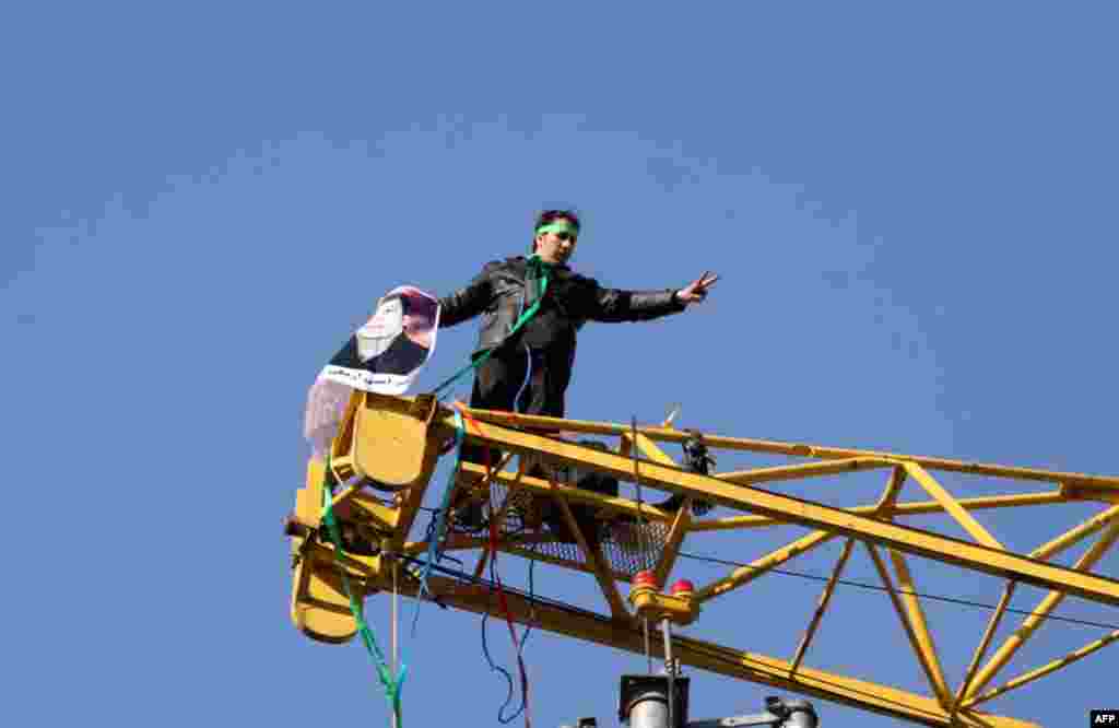 A man wearing a green headband stands on top of a crane before attempting suicide in central Tehran