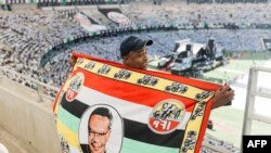 FILE — An Inkatha Freesdom Party (IFP) supporter holds a flag depicting former IFP leader Mangosuthu Buthelezi, during the IFP election manifesto launch at the Moses Mabhida Stadium in Durban on March 10, 2024.