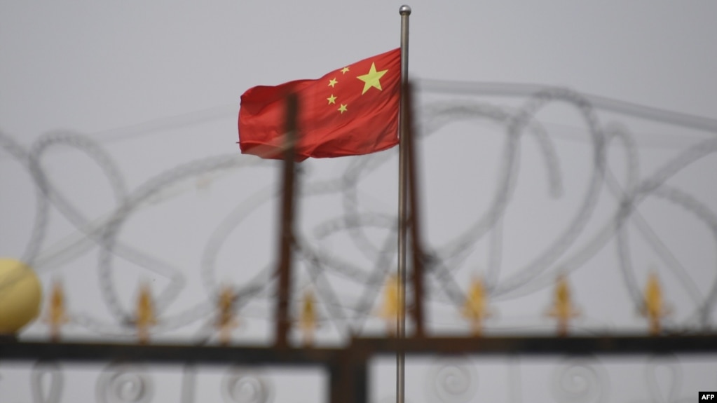 资料照片:在新疆喀什市以南的一个居住区,一面中国国旗在铁丝网后面飘扬。(2019年6月4日)