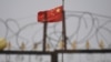 资料照：中国国旗在新疆喀什南部地区一处建筑物的围栏铁丝网后飘扬。（2019年6月4日）