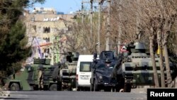 FILE - Military and police armored vehicles are parked in Baglar district, which is partially under curfew, in the Kurdish-dominated southeastern city of Diyarbakir, Turkey, March 17, 2016. 