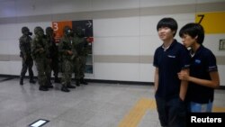 Dua siswa Korea Selatan berjalan melewati tentara (mengenakan masker gas) dalam latihan bersama militer Korea Selatan dan AS di sebuah stasiun kereta bawah tanah di Seoul (19/8). 