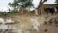 A picture released by Oxfam and taken on17 Aug 2010 shows people standing near homes destroyed by flooding near Zinder