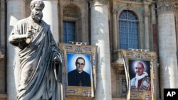 Tapices del arzobispo católico Oscar Romero, a la izquierda, y el Papa Paulo VI cuelgan de un balcón de la fachada de la Basílica de San Pedro en el Vaticano, 13 de octubre de 2018.