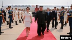 北韓領導人金正恩和夫人李雪主2018年6月19日抵達北京，中共中央政治局常委王滬寧迎接。