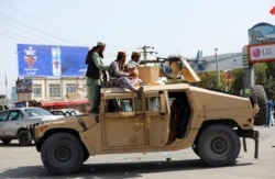 Taliban fighters stand guard in front of the Hamid Karzai International Airport, in Kabul, Afghanistan, Aug. 16, 2021.