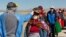 A health worker checks the temperature to residents from surrounding communities heading to the weekly food market in Coata, Peru, on July 8, 2020.