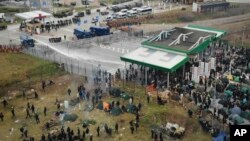 In this image taken with a drone Polish servicemen use a water cannon during clashes between migrants and Polish border guards at the Belarus-Poland border near Grodno, Belarus, Nov. 16, 2021. 