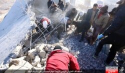 FILE - This image posted online Dec. 6, 2015, by supporters of the Islamic State militant group on an anonymous photo sharing website shows Syrians inspecting a damaged building in the aftermath of an airstrike that targeted areas in Raqqa, Syria.
