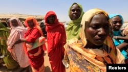 Displaced women wait to receive food at a food distribution center as special envoys and diplomats arrive for a meeting to discuss the progress of a peace treaty in Darfur, at Shangli Tobay village in North Darfur, June 18, 2013.