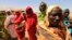Displaced women wait to receive food at a food distribution center as special envoys and diplomats arrive for a meeting to discuss the progress of a peace treaty in Darfur, at Shangli Tobay village in North Darfur, June 18, 2013.