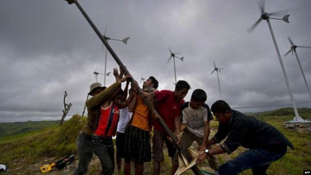 Warga menegakkan kincir angin di lapangan turbin angin kecil di desa di Pulau Sumba, Nusa Tenggara Timur. (Foto: AFP)