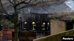Firefighters stand near a building at London Zoo following a fire that broke out at a shop and cafe at the attraction, in central London, Dec. 23, 2017.