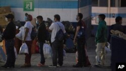 Guatemaltecos deportados desde Estados Unidos, que usan tapabocas como precaución contra el contagio del coronavirus, entran las instalaciones en las que guardarán cuarentena en la ciudad de Guatemala.